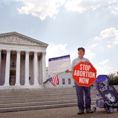 An anti-abortion protester holds a stop sign and the Ten Commandments on the sidewalk in front of the U.S. Supreme Court on May 14, 2001 in Washington, D.C. 